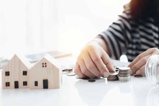 Woman's hand saving a coin for planning, housing and property financial concept