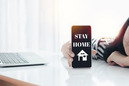 Woman's hand holding smartphone with alert notification for self-quarantine, social distancing, staying and working at home in coronavirus or Covid-2019 outbreak situation concept