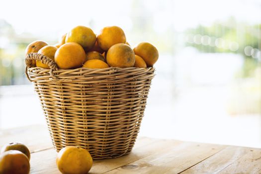 Orange in the wicker basket against blurred outdoor background for fruit and eating concept