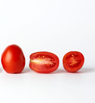 ripe red whole tomatoes and pieces on a white background, autumn harvest for salad and cooking