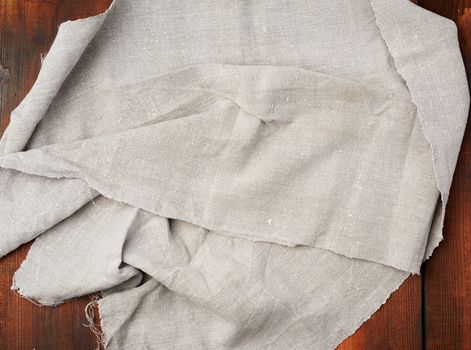 folded gray linen towel on wooden background, top view, copy space