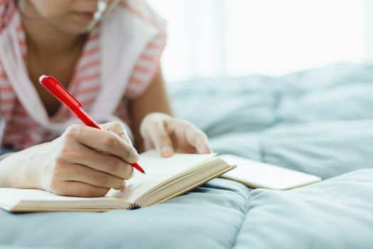 Woman taking a note in bed for self-quarantine, social distancing, staying and working at home in coronavirus or Covid-2019 outbreak situation concept