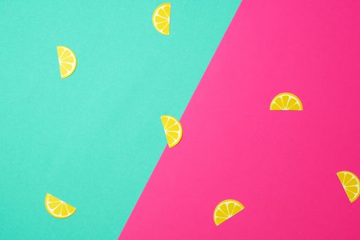 abstract green-pink background with paper yellow lemon slices, close up