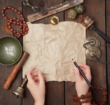 tibetan religious objects for meditation and alternative medicine, empty brown sheet of paper on a brown  wooden background, top view, copy space