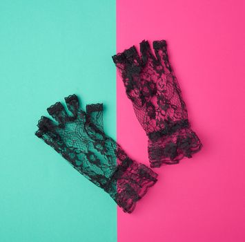 black lace gloves on a pink-green background, top view