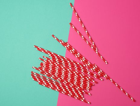 red paper tubes for a cocktail on a multi-colored background, concept of rejection of plastic and the use of recyclable materials