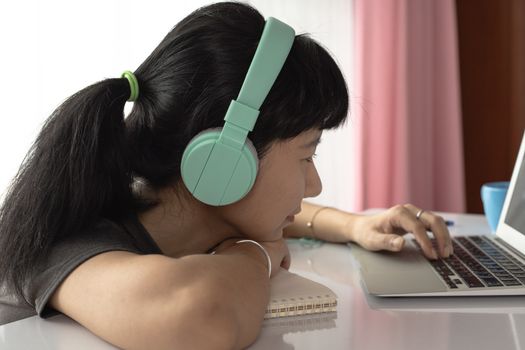 Woman wearing headphones, using laptop and staying at home for self-quarantine, staying home and social distancing in coronavirus or Covid-2019 outbreak situation