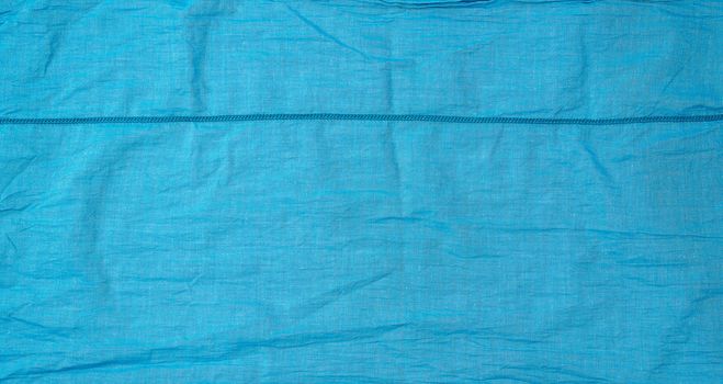 fragment of blue cotton fabric with a seam, full frame, close up