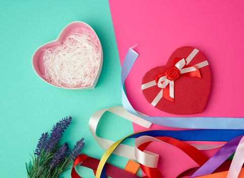 open red heart-shaped gift box with a bow on a pink green background, top view, festive backdrop