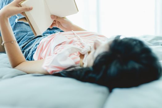 Woman reading a book in bed for self-quarantine, social distancing, staying and working at home in coronavirus or Covid-2019 outbreak situation concept