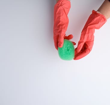 hand in an orange glove holds a kitchen sponge, white background