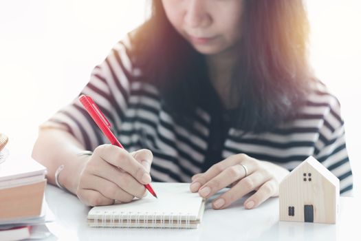 Woman writing on the paper and working at home for business, self-quarantine, staying home and social distancing in coronavirus or Covid-2019 outbreak situation concept