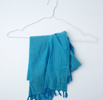 blue textile scarf hanging on a white metal hanger, flat lay