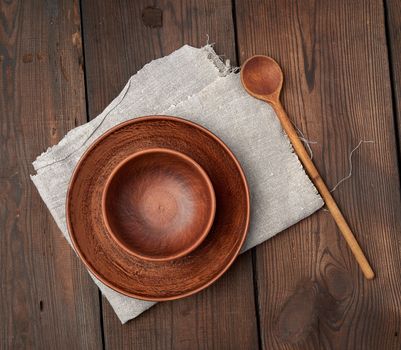 empty brown ceramic plates and wooden spoon on a wooden table, top view