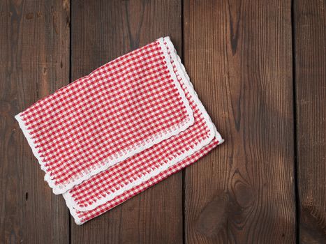 white red checkered kitchen towel on a brown wooden background, picnic background, copy space