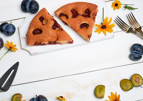  slices of biscuit plum cake on a white wooden board and fresh fruits, top view
