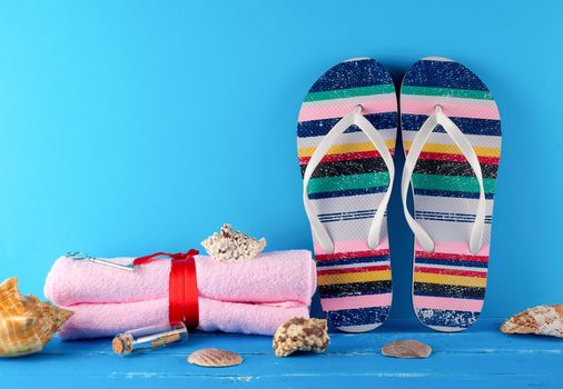 pair of female beach slippers and a towels on a blue background, concept of a vacation at sea