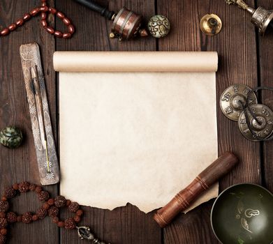 tibetan religious objects for meditation and alternative medicine, empty brown sheet of paper on a brown  wooden background, top view, copy space