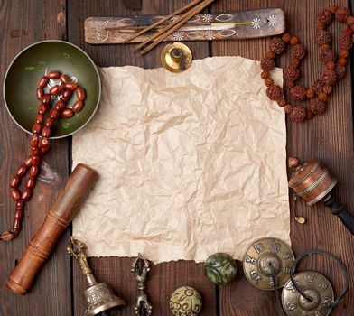tibetan religious objects for meditation and alternative medicine, empty brown sheet of paper on a brown  wooden background, top view
