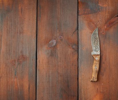 vintage steel sharp knife on a brown wooden table made of boards, top view, place for text