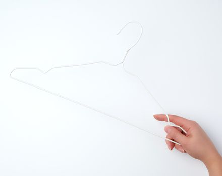 hand holds a white iron empty hanger on a white background, close up