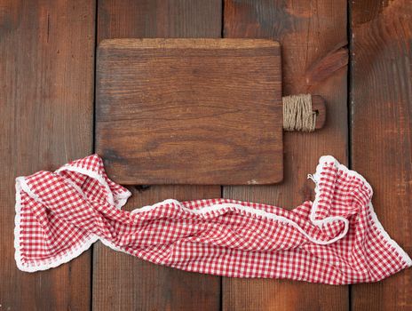 empty very old rectangular cutting wooden board and red kitchen towel on a wooden surface
