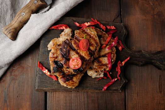 grilled pork pieces of meat on a grill lie on a vintage wooden board, close up