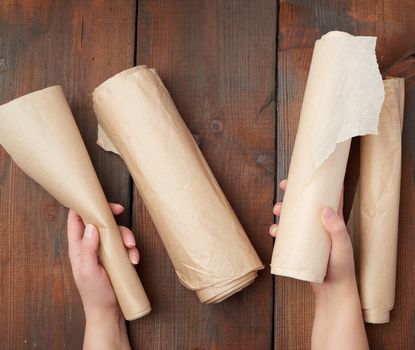 four rolled rolls of brown parchment paper on a wooden surface, top view