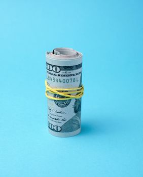 rolled up and connected rubber band banknotes of american dollars on a blue background