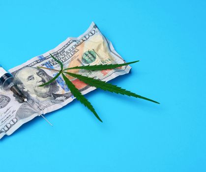 cash US dollars, green hemp leaf and empty plastic syringe, drug addiction concept
