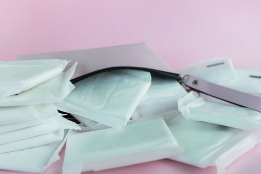 Feminine sanitary napkin, an absorbent item worn by a woman while menstruating, with women's bag on pink background for hygiene and health concept