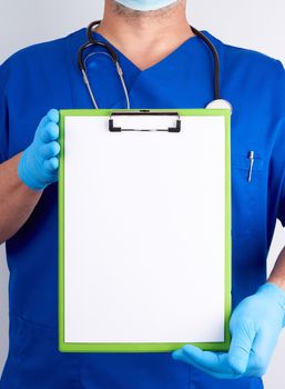 doctor in blue uniform and latex gloves holds a green holder for sheets of paper, empty space for writing text, white background