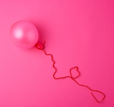 Inflated pink air balloon on the pink background, close up