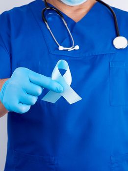 doctor in blue uniform and latex gloves holding a blue ribbon in his hand, symbol of the fight and treatment of prostate cancer