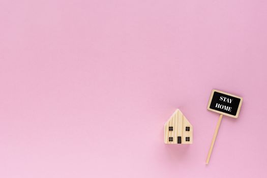 Wooden house model with stay home text on pink background for self-quarantine and staying home in coronavirus or Covid-19 situation concept