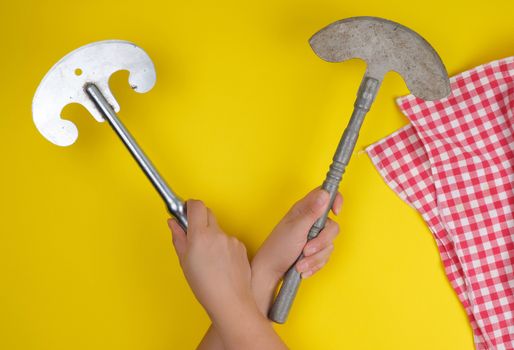 two hands holding vintage sharp kitchen knives for meat and vegetables, yellow background