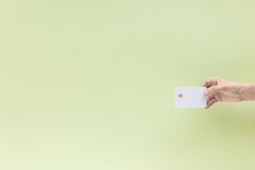 Hand holding blank credit chip card on green background with copy space for business and finance concept