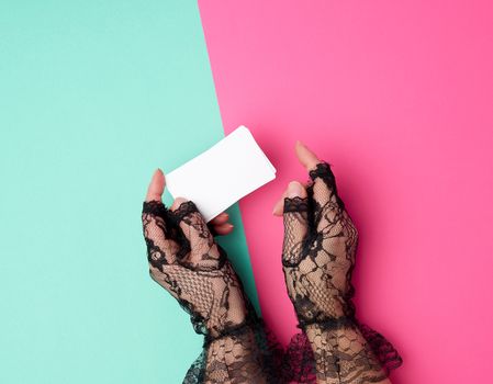 two female hands holding a stack of empty white paper business cards on a colored background, top view