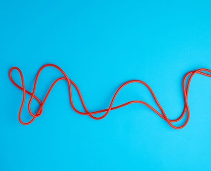 fragment of a red jump rope for sports on a blue background, two lines
