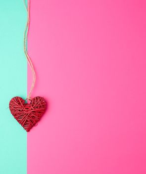 red wicker decorative heart  hanging on a brown rope, copy space