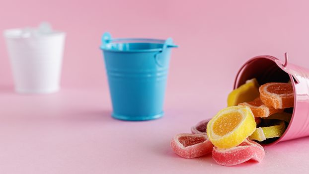 Colourful fruit Jelly candy in a pink bucket against pink background for food and snack concept