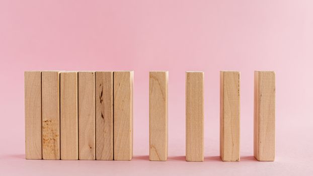 Wooden toys arranged in a horizontal row on pink background for leisure activities concept