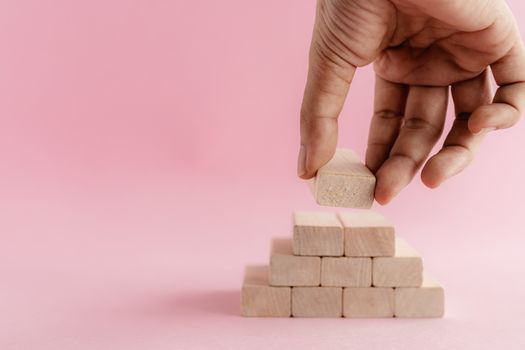 Hand putting the wooden toy on pink background for leisure activities concept