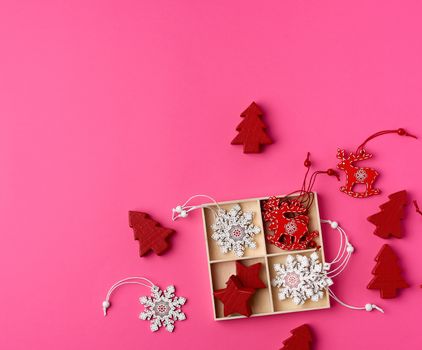 wooden carved Christmas decorations for the holiday tree on a pink background, top view
