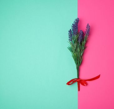lavender bouquet and red ribbon on a color background, top view, copy space