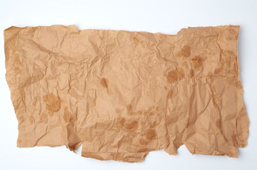 torn crumpled piece of brown paper with grease stains on a white background, top view