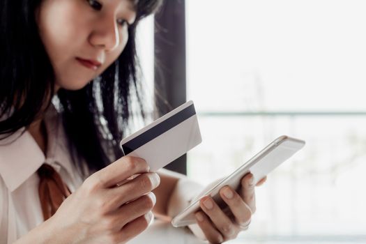 Asian woman holding a credit card and using smartphone for online shopping and payment concept