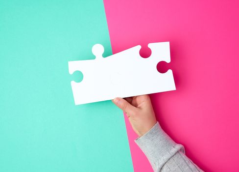 blank white big puzzles in female hand on green ponk background, copy space