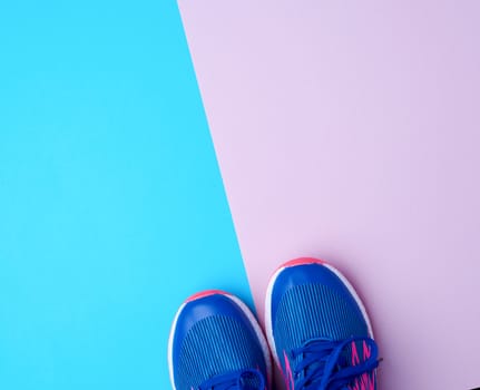 pair of sports sneakers with blue laces on a colored abstract background, top view, place for test