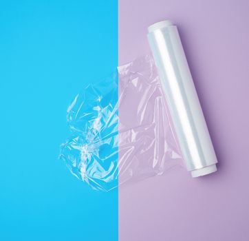 roll with transparent white polyethylene for wrapping products and packaging goods on a colored background, top view